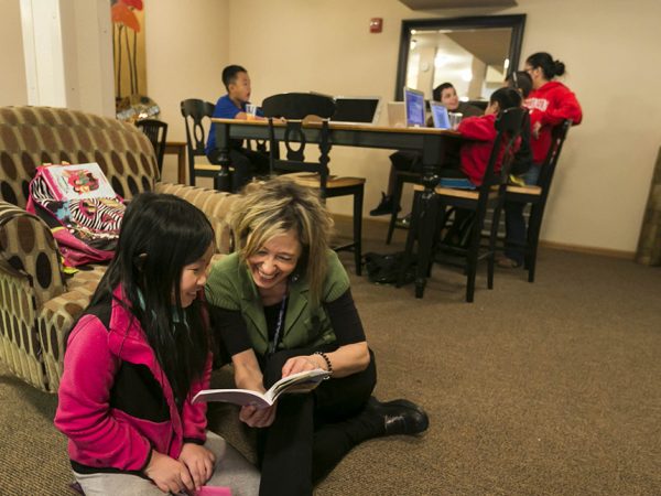 Teacher Silvina Clazmer reads with Athena Vang, left, 8, 3rd grade, at the Rolling Prairie Apartments in Sun Prairie in an after school program called the Homework Club March 17, 2015, in Sun Prairie. Clazmer wrote a grant for financial assistance to help with computers and other materials for the club. (Photo © Andy Manis)