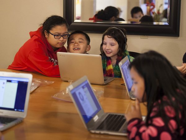 Mentor Vanessa Lovan, left, 18, works with 2nd graders Leon Vang, 8, and Maeli Hamilton, 8, on an interactive reading exercise at the Rolling Prairie Apartments in Sun Prairie in an after school program called the Homework Club March 17, 2015, in Sun Prairie. (Photo © Andy Manis)